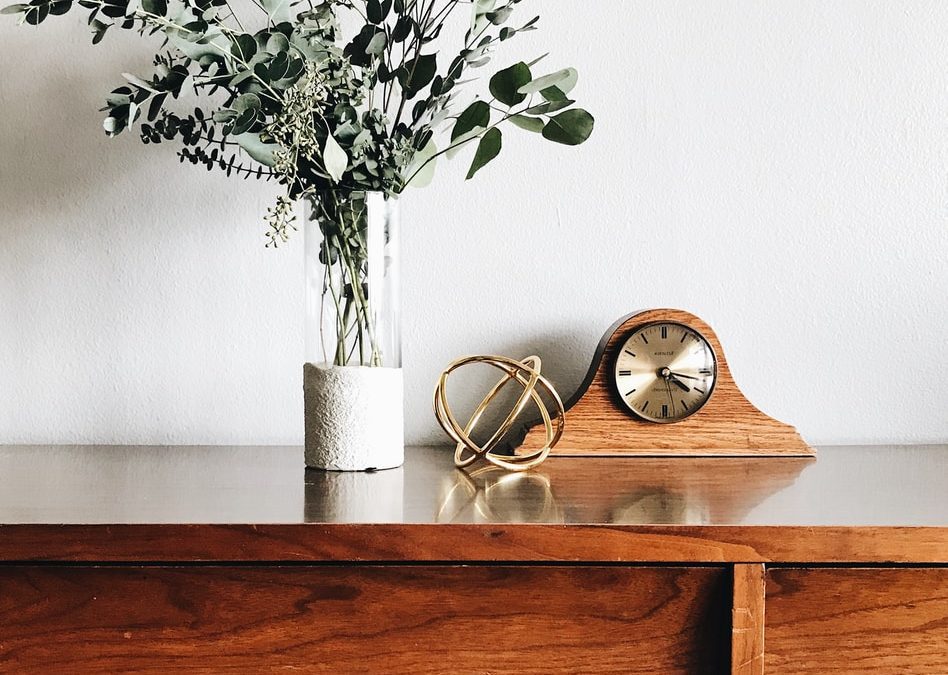 brown wooden framed analog mantle clock near gray petaled flower centerpiece